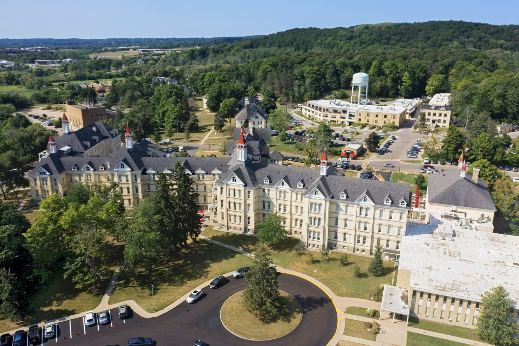 Historic large building surrounded by trees and parking.