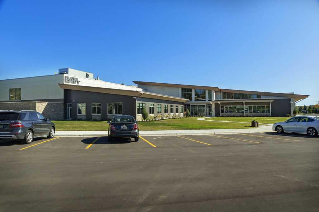 Modern office building with parked cars, clear sky.