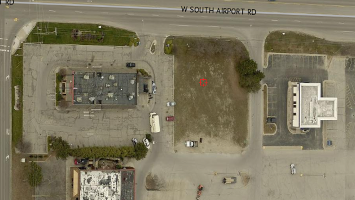 Aerial view of parking lots and buildings next to road.