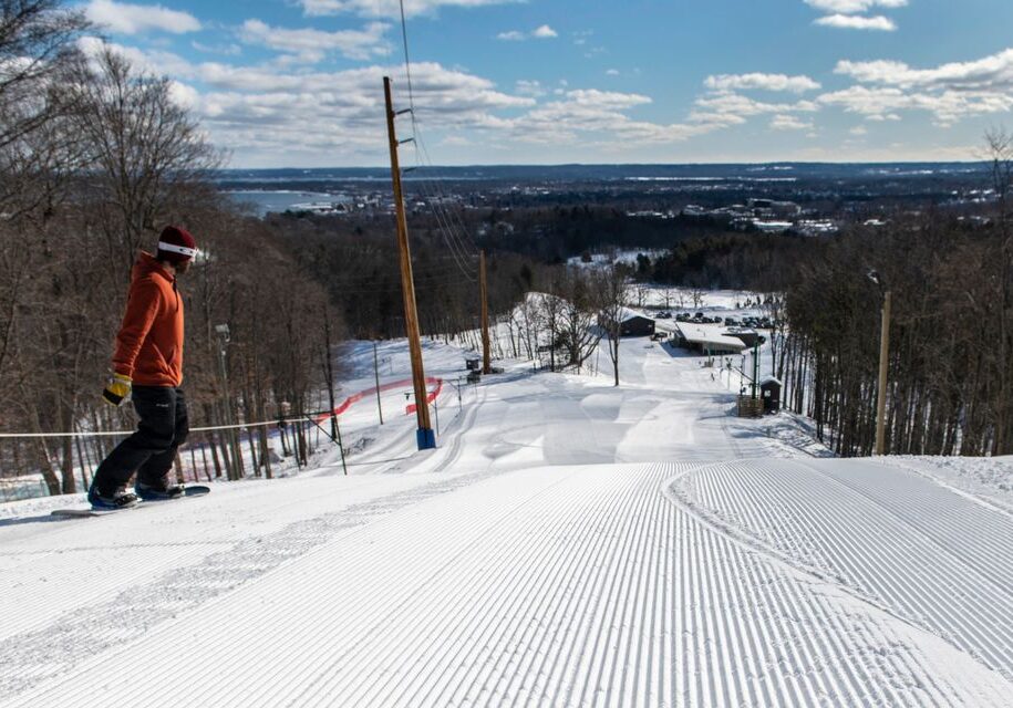 Snowboarder on groomed snowy slope with scenic view